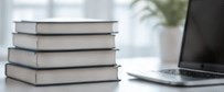 Stack of reference books beside a laptop